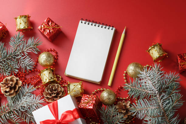 istock Christmas composition with notepad and a pencil for writing wishes with Christmas tree decorations on a red background. 1373142408