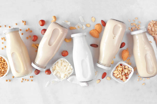Vegan, plant based, non dairy milk milk bottles with scattered ingredients over white marble Vegan, plant based, non dairy milk. Variety in milk bottles with scattered ingredients. Above view over a white marble background. coconut milk photos stock pictures, royalty-free photos & images