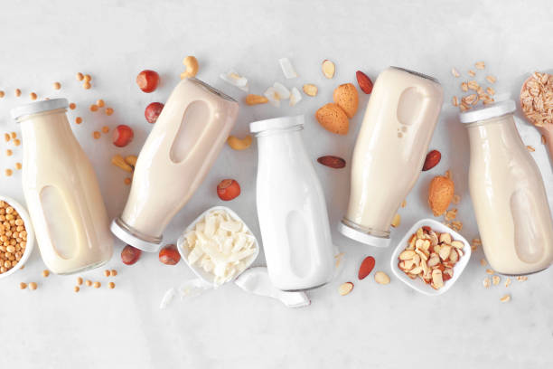 Vegan, plant based, non dairy milk milk bottles with scattered ingredients over white marble Vegan, plant based, non dairy milk. Variety in milk bottles with scattered ingredients. Above view over a white marble background. dairy product stock pictures, royalty-free photos & images