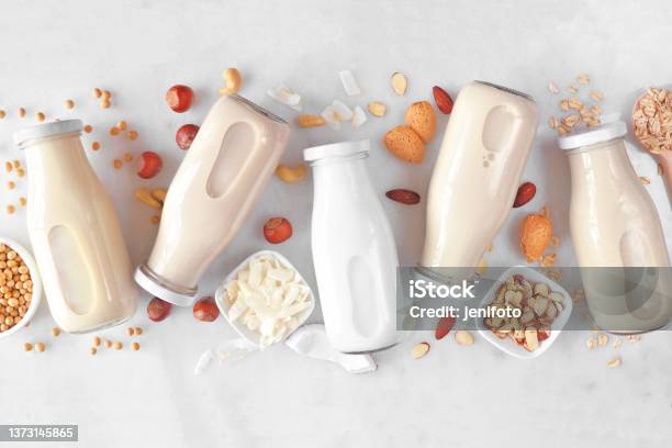 Vegan Plant Based Non Dairy Milk Milk Bottles With Scattered Ingredients Over White Marble Stock Photo - Download Image Now