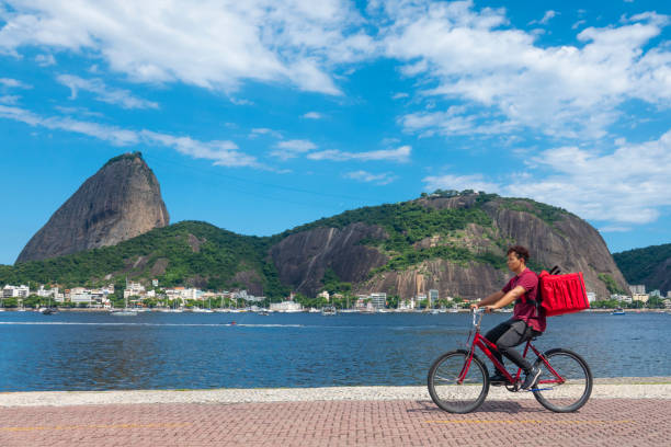 25-летний мужчина осуществляет доставку на дом с помощью велосипеда - rio de janeiro guanabara bay urban scene cityscape стоковые фото и изображения