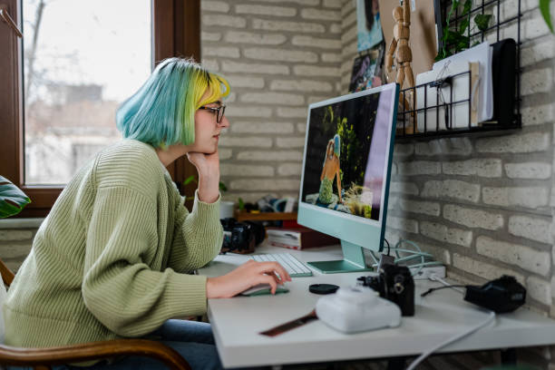 Millennial photographer working on her photos at home office stock photo