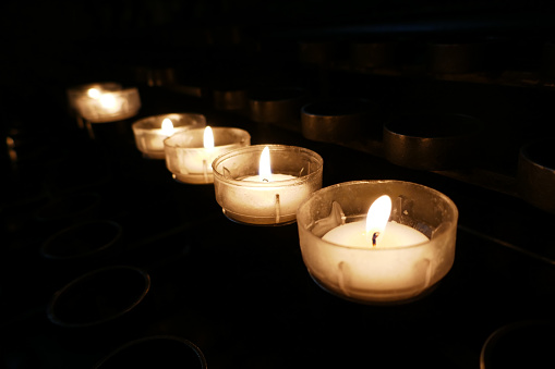 Row with prayer tea lights in a roman catholic church. The candles are lighted to underline a prayer