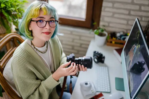 Photo of Millennial photographer working on her photos at home office