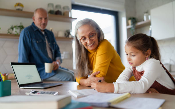 niña pequeña con abuelos mayores haciendo la tarea de matemáticas en casa. - relación humana fotografías e imágenes de stock