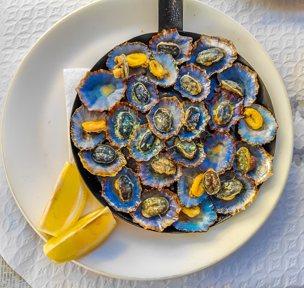 Cooked limpets served in a cast iron with a lemon slices in a restaurant in Madeira island