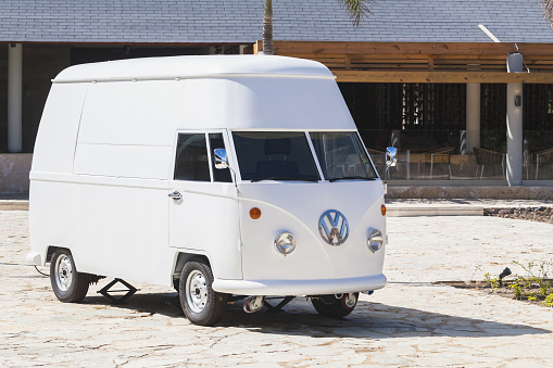 Bavaro, Dominican Republic - January 15, 2020: White Volkswagen Type 2 van, custom trade bus modification. Light commercial vehicle stands on a town square on a sunny day