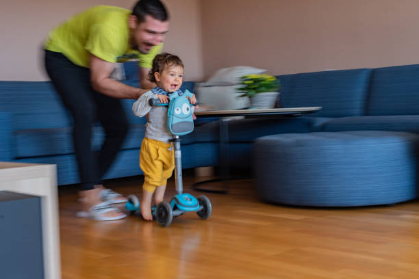 istock Boy riding scooter whit his father at home 1373154896
