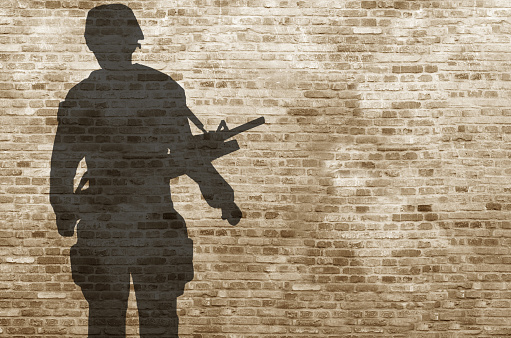 Photographic illustration of a soldier as shadow seen on a brickwall