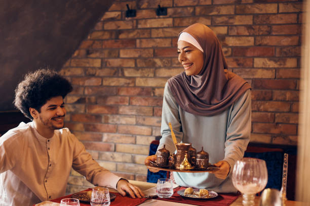 istock Happy Middle Eastern woman serving traditional Arabic coffee while having dessert with her husband. 1373156632
