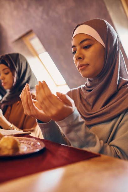 istock Middle Eastern woman reciting dua while praying with her family at dining table on Ramadan. 1373156653