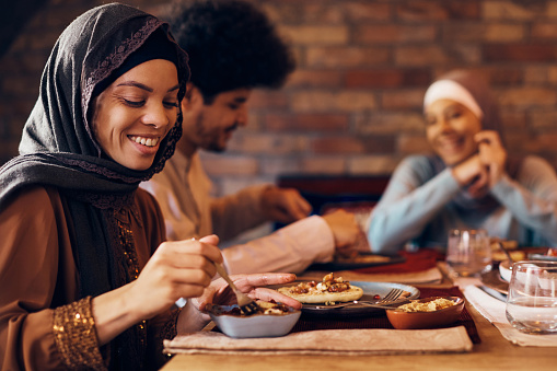 Joven musulmana feliz disfrutando de la comida de Ramadán con sus amigos. photo
