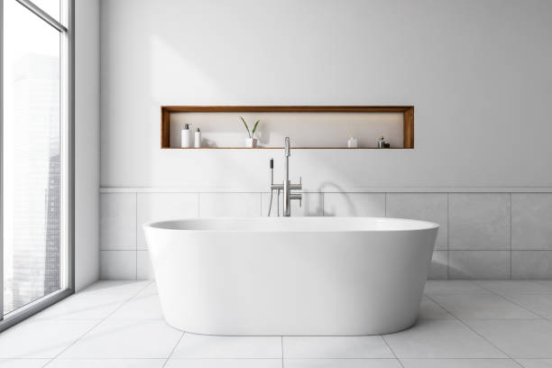 istock Light bathroom interior with bathtub and deck with gels, window 1373161478