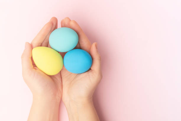 istock Women's hands hold colorful Easter eggs on a pink background 1373161575
