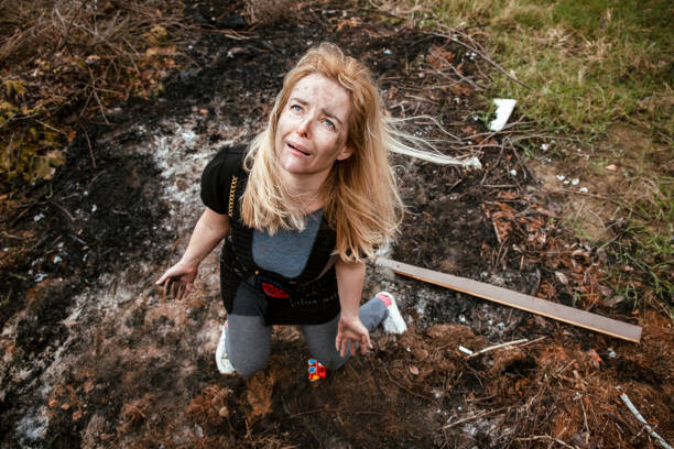 Crying sad hopeless blonde Woman in burned and destroyed house, ruined after fire. Natural disaster, Extreme weather, Bombing, war concept. Above view