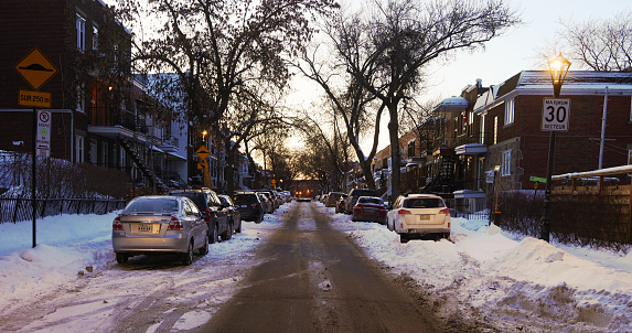 Montreal Rosemont area one way residential street at twilight, with cars parked on each side.