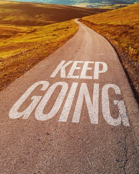 Keep going motivational message on asphalt road through countryside landscape stock photo
