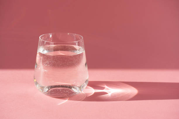 bicchiere di acqua fresca e pura. luce dura, ombra profonda - pink glasses foto e immagini stock