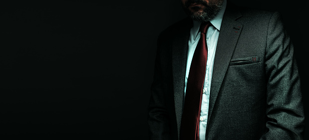 Panoramic portrait of senior executive businessman over dark background, low key image with selective focus