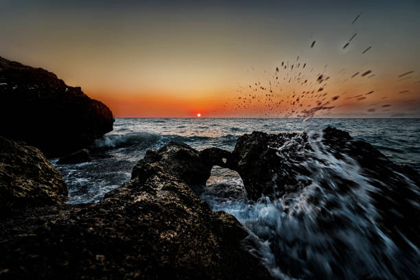 Beautiful sunset light touches the wave approaching the rocks.