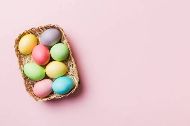 Multi colors Easter eggs in the woven basket on colored background . Pastel color Easter eggs. holiday concept with copy space stock photo