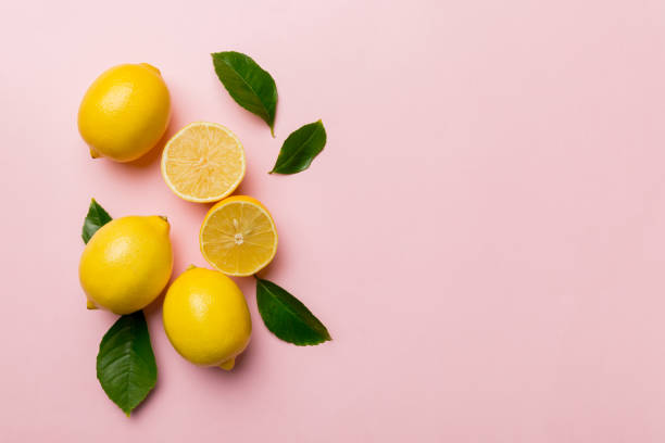 istock Many fresh ripe lemons with green leaves on colored background, top view, space for text 1373171125
