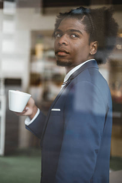 istock elegant african businessman drinking coffee, vertical portrait through cafe window 1373173302