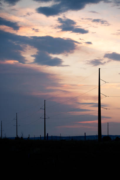 Power lines silhouette at sunset with cloudy sky