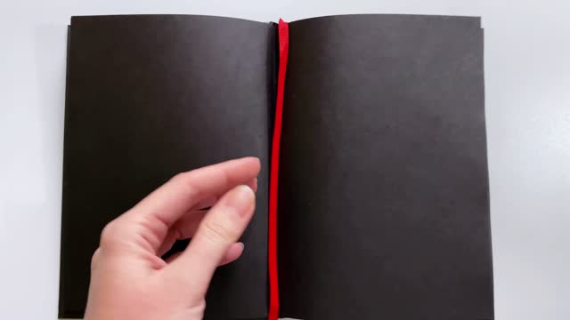 Close-up demonstration of a notebook with black paper for inscriptions in white ink