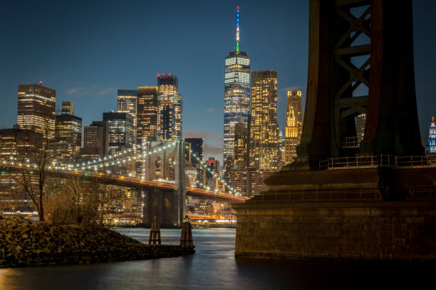die brooklyn bridge, der freedom tower und lower manhattan bei nacht - blurred motion bridge business blue stock-fotos und bilder