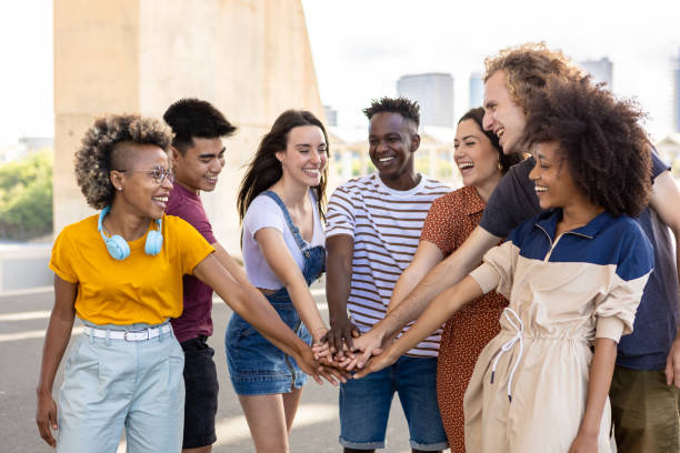 Group of young student friends with hands on stack showing international unity stock photo