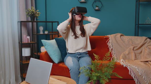 istock Young girl use virtual reality headset glasses at home play 3D video game making gestures with hands 1373188656