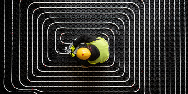 istock Plumber installing heating pipe, white spiral on black background 1373189767