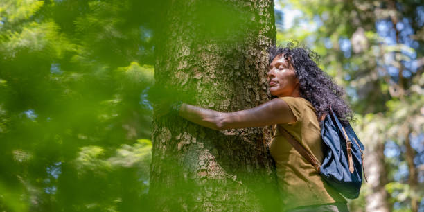 istock Female environmentalist hugging grown tree in forest on sunny day 1373189852
