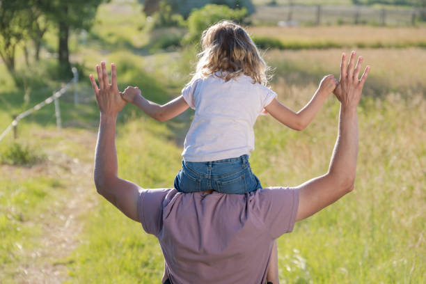 istock Daughter riding on dad's shoulders and holding his thumbs 1373189875