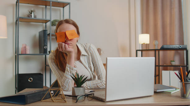 istock Tired woman teacher using laptop computer with funny stickers on eyes sleeps at workplace, napping 1373190035