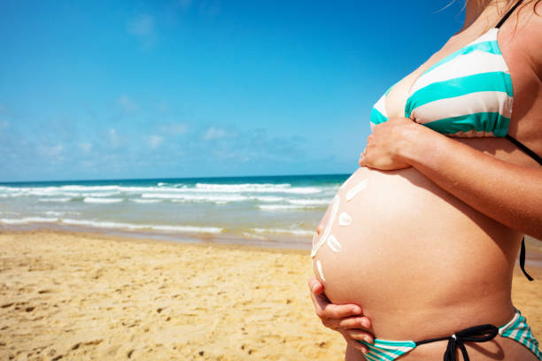 Close-up of big pregnant woman's belly wearing bikini stand on the beach