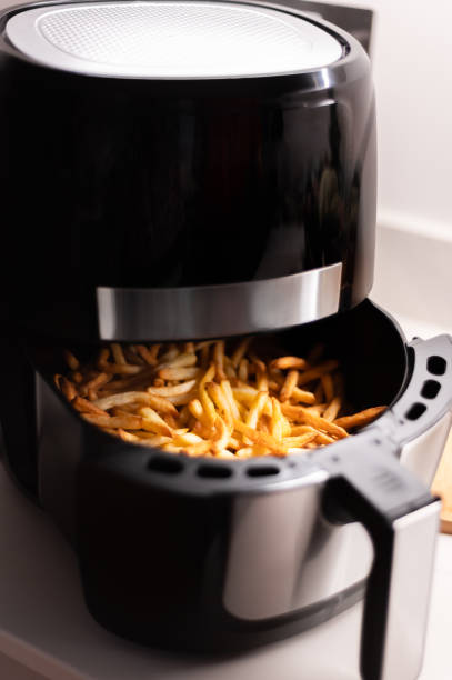 Air fryer with french fries on the worktop stock photo