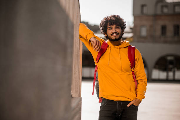 istock Dark-haired young guy in orange hoodie with a backpack 1373190773