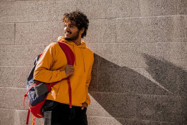 istock Curly-haired young man with a backpack in the street 1373190780