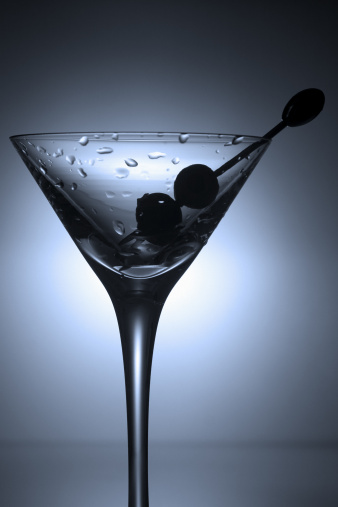 A chilled martini glass garnished with two olives and a stainless steel toothpick.