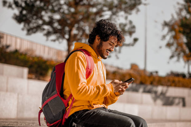 istock Young man in orange with a phone in hands 1373190791