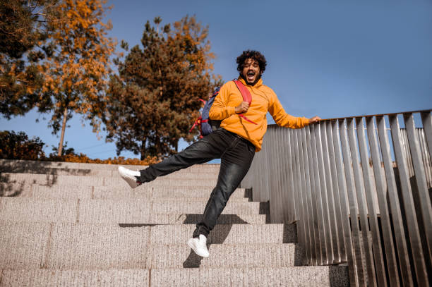 istock Young man in orange hoodie feeling enjoyed and jumping 1373190817