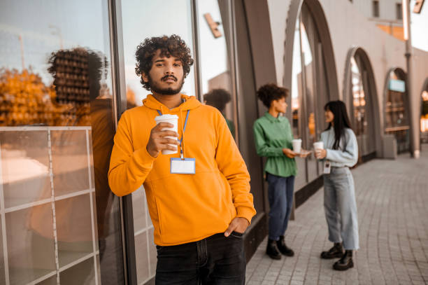 istock Young man in orange hoodie with a no-spill cup in hands 1373190842