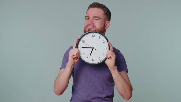 istock Young man holding clock watch, hiding, checking time on clock, running late to work being in delay 1373195107