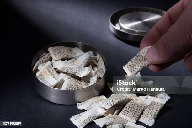 Closeup Of Metallic Swedish Snus Can With White Portions Of Smokeless Tobacco Pouches Against A Dark Background Stock Photo - Download Image Now