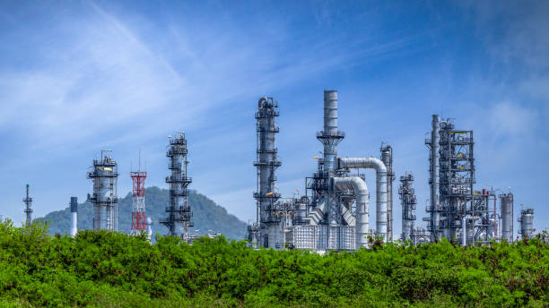 ölraffinerieanlage aus industriezone, petrochemische öl- und gasindustrie mit baum- und blauem himmelshintergrund, öllagertank und pipelinestahl der raffineriefabrik, ökosystem- und gesunde umweltkonzepte. - ölindustrie stock-fotos und bilder