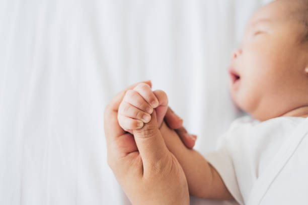 istock Mother touch her newborn baby hand gently on white bed 1373215459