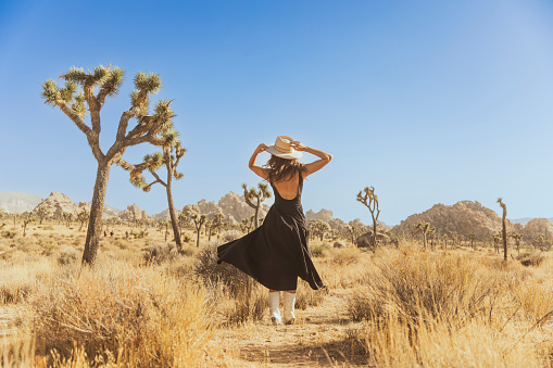 Woman twirling in hat and flowy dress in Joshua Tree National Park