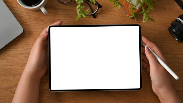 デジタルタブレットを持つ女性の手と作業テーブルまたは研究テーブル - ipad digital tablet computer monitor blank ストックフォトと画像